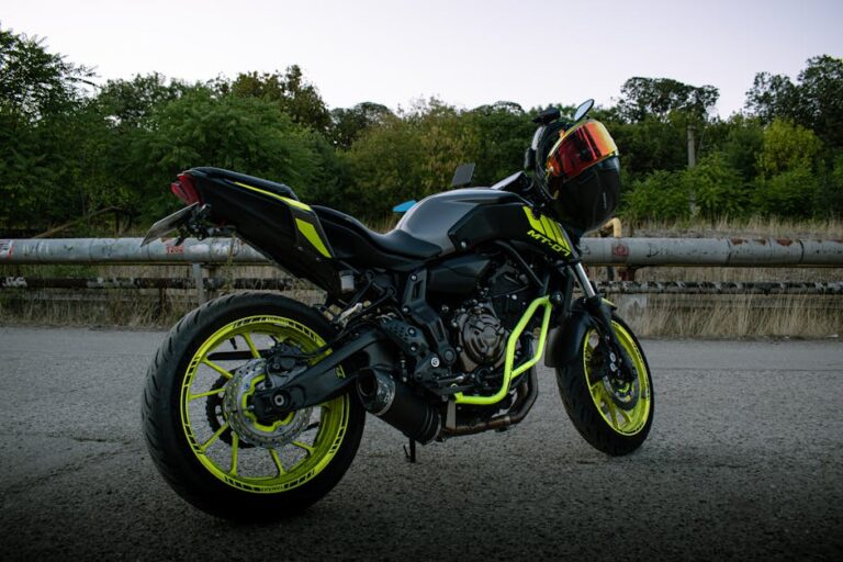 A sleek sport motorcycle with vibrant neon accents parked outdoors on a road at dusk.