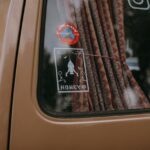 Close-up of a vintage car window adorned with rocket-themed stickers and curtains.