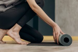 A woman rolling out a yoga mat for an indoor fitness routine, emphasizing calmness and focus.