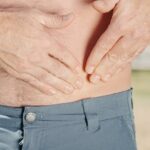 A person holding their abdomen, indicating possible discomfort or injury.