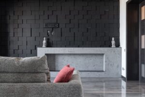 Stylish interior design featuring a gray sofa and artistic textured black wall.
