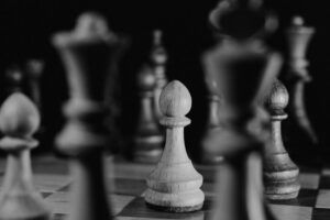 Artistic black and white photo of wooden chess pieces on a board, emphasizing strategic gameplay.