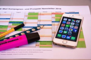 A desk setup featuring a planner, pens, and a smartphone displaying app icons, ideal for productivity.