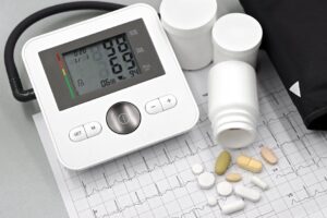 Blood pressure monitor with pills on ECG sheet, essential for heart health management.
