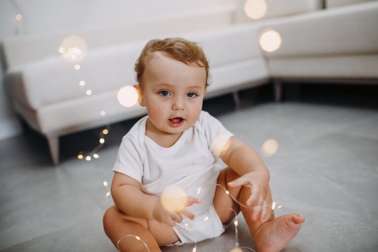 Cute baby sitting on the floor with string lights, in a cozy indoor setting.