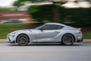 Side view of a fast silver sports car in motion on an urban road.
